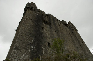 A close-up photo of the castle, large and looming, against a grey sky.